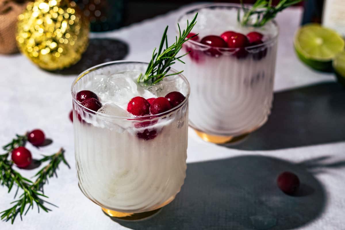 Margaritas garnished with cranberries and fresh rosemary.