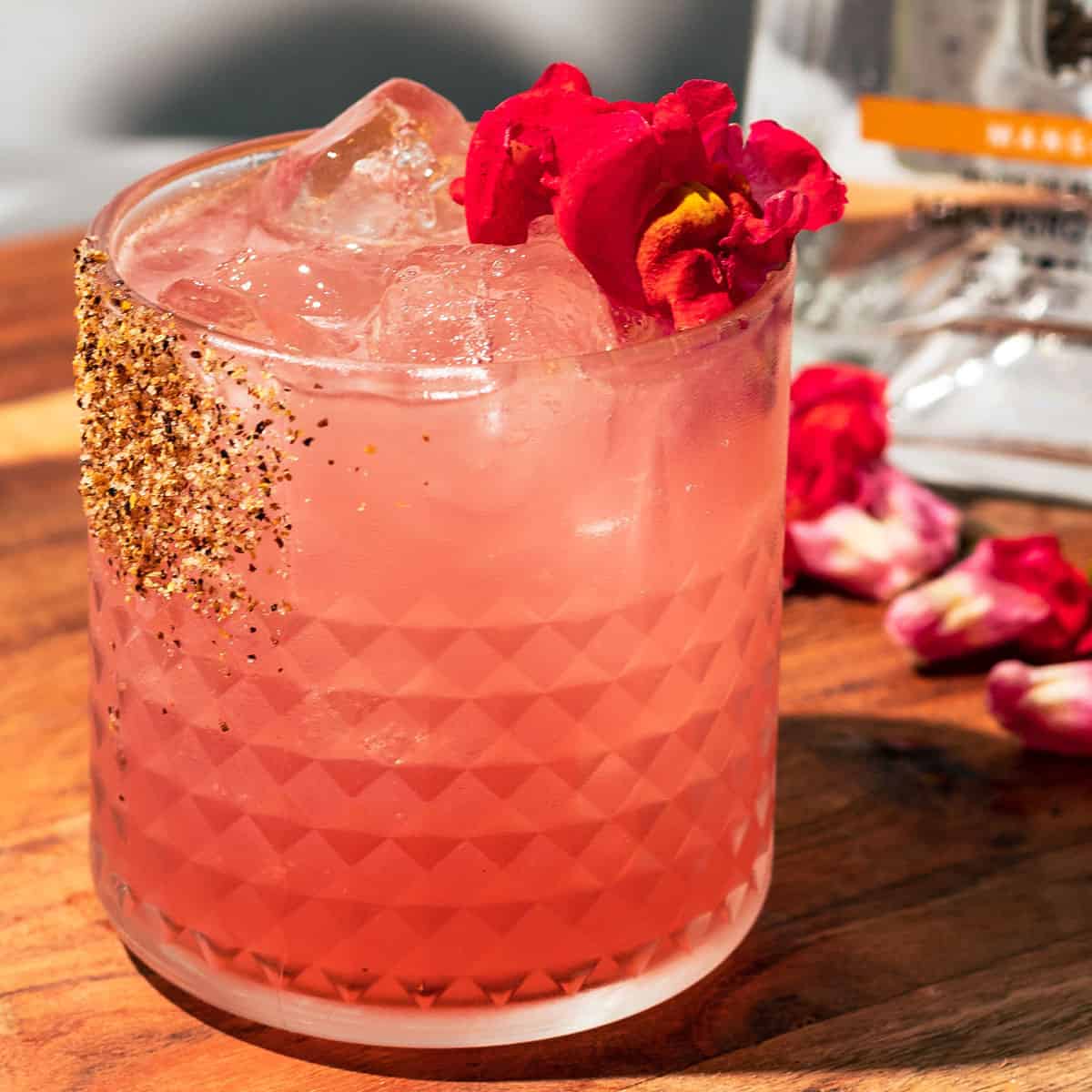 The hibiscus margarita garnished with a pink edible flower and a tajin rim.