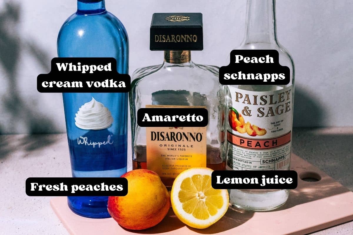 Ingredients for the cocktail spread out on a pink surface.