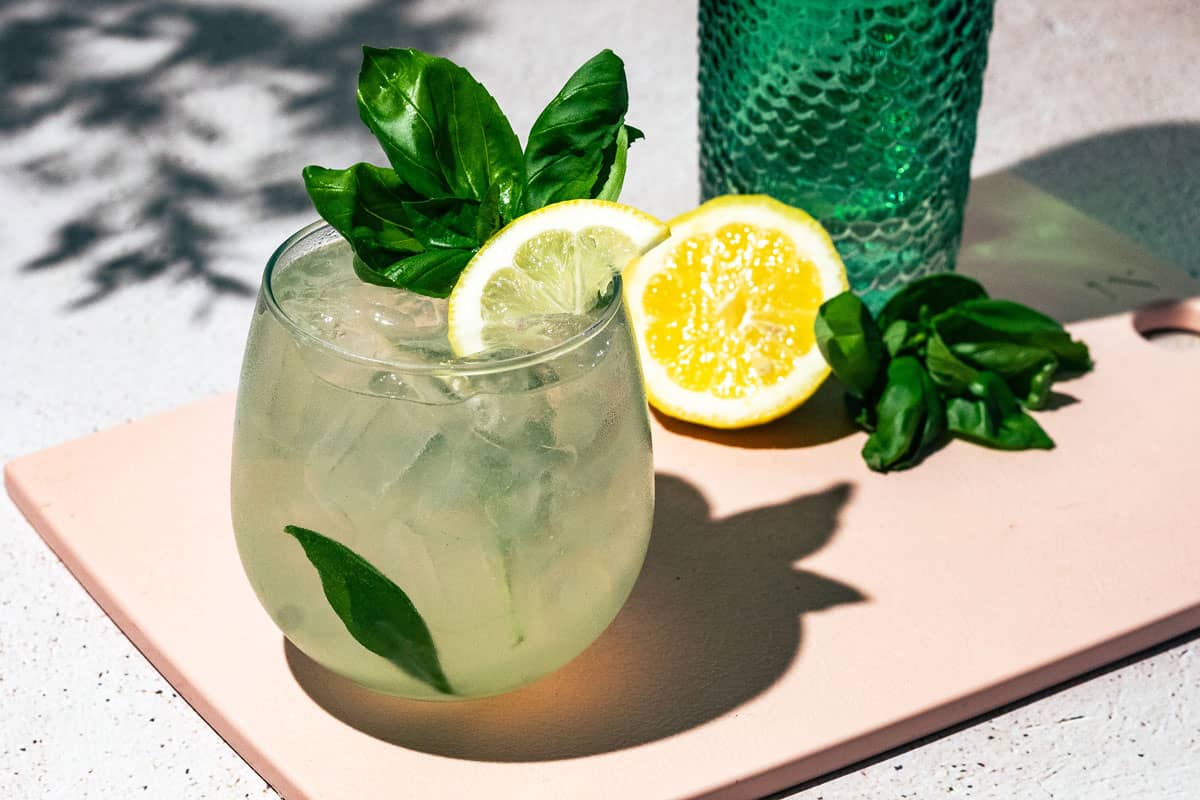Gin and tonic garnished with lemon and fresh basil.