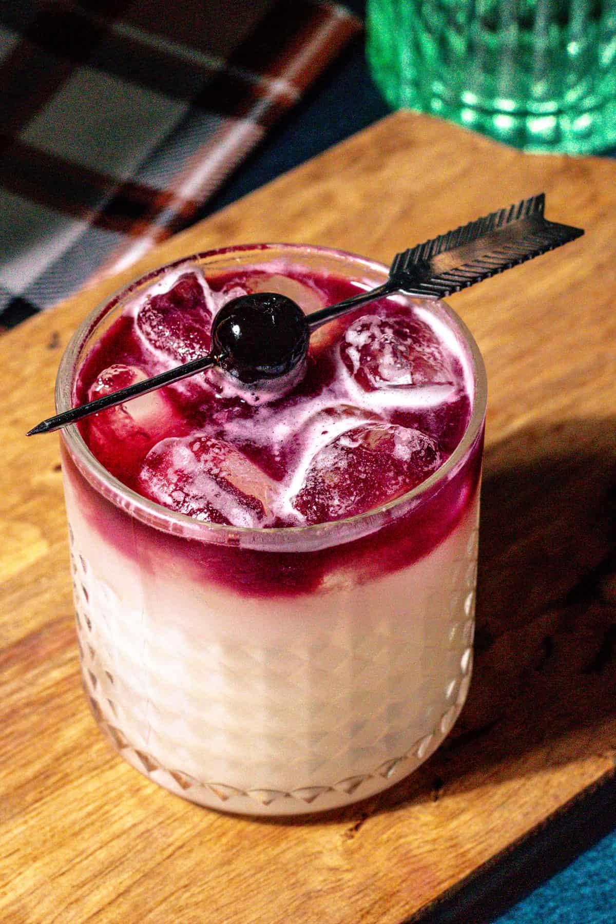 The Red Jamie with a red wine floater and garnished with a cherry arrow skewer.