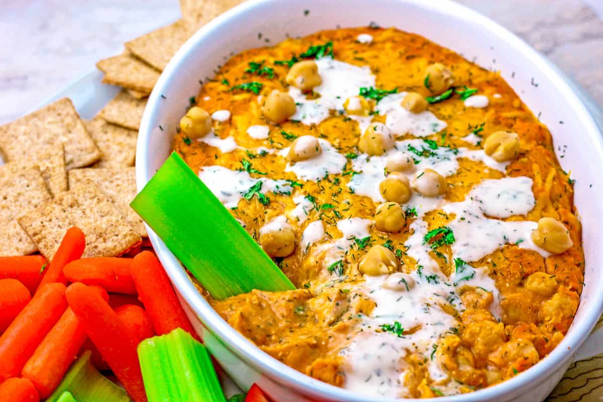 A celery stick dipped into the Buffalo Chickpea Dip.